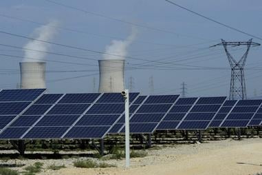 Photo of photovoltaic panels in front of the cooling towers of the Tricastin nuclear power plant in Provence.